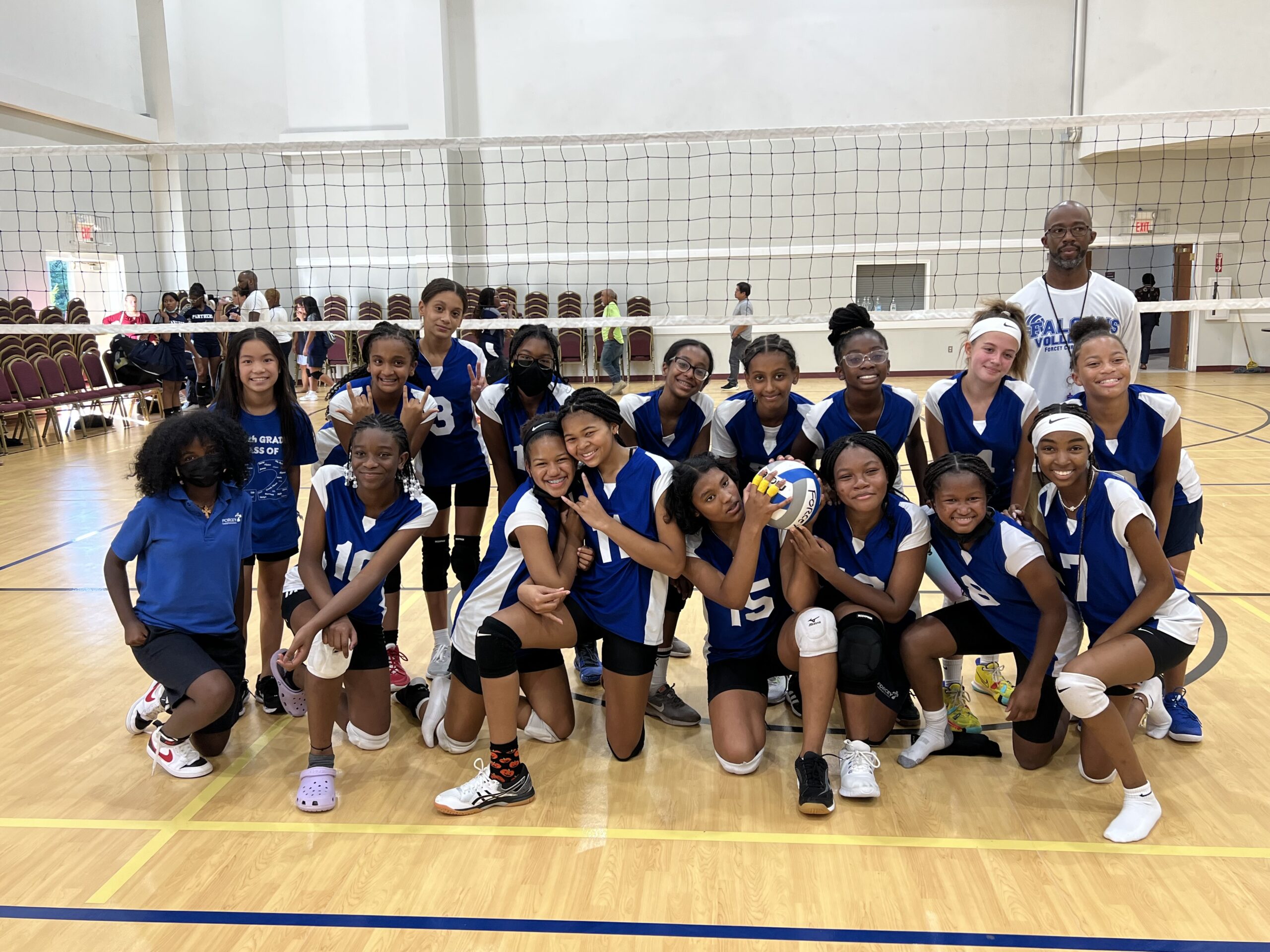 Lady Falcons with Coach posing by the net